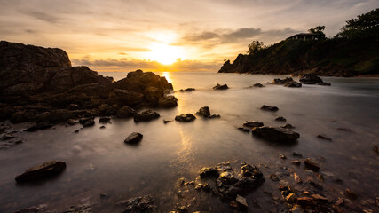 Fototapeta na wymiar Sand beach among rocks on evening sunset in the concept of summer landscape