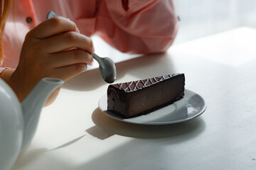 Cheesecake on a plate in the hands of a girl in a pink blouse