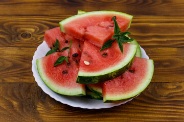 Fresh ripe sliced watermelon in white plate on a wooden table