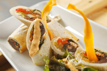 Chicken wrap with beans and peppers accompanied by salad and cheddar cheese dressing.
