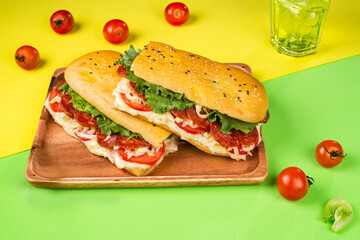 Sandwich with chorizo, cheese and vegetables on yellow and green background with copy space 