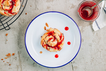 Freshly baked sweet yeast buns with berry jam on cooling rack.