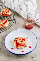 Freshly baked sweet yeast buns with berry jam on cooling rack.