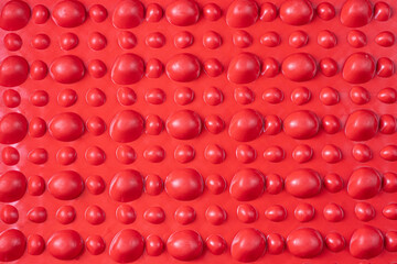 Red orthopedic mat in the form of small stones for foot massage. Prevention of children's flat feet.