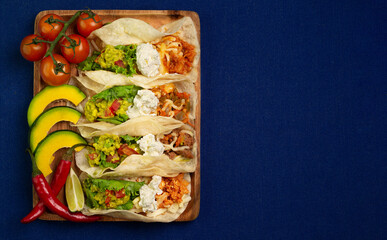 Mexican food - delicious taco shells with ground beef, chicken, vegetables over blue background Top view. Banner menu with space place