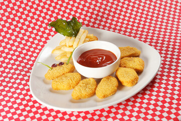 Chicken nuggets with ketchup served with french fries.