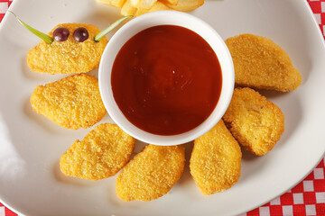 Chicken nuggets with ketchup served with french fries.