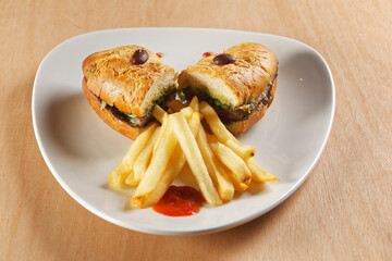 Beef baguette with tomato, lettuce, avocado and dressings accompanied by french fries.