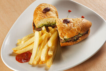 Beef baguette with tomato, lettuce, avocado and dressings accompanied by french fries.