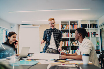 Delighted architect working on blueprint near diverse colleagues