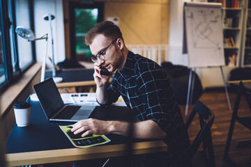 Caucasian male programmer sitting at table desktop and using mobility connection for making...