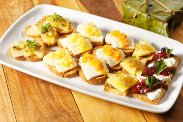 Snacks of toasted bread with Mozarella cheese, fresh cheese and Manchego cheese with strawberry, kiwi and pineapple marmalade.