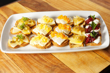 Snacks of toasted bread with Mozarella cheese, fresh cheese and Manchego cheese with strawberry, kiwi and pineapple marmalade.