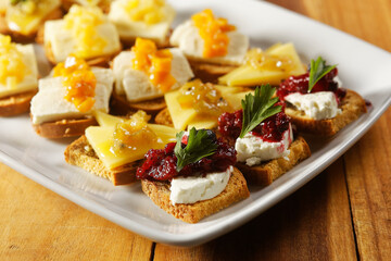 Snacks of toasted bread with Mozarella cheese, fresh cheese and Manchego cheese with strawberry, kiwi and pineapple marmalade.