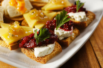 Snacks of toasted bread with Mozarella cheese, fresh cheese and Manchego cheese with strawberry, kiwi and pineapple marmalade.