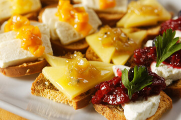 Snacks of toasted bread with Mozarella cheese, fresh cheese and Manchego cheese with strawberry, kiwi and pineapple marmalade.