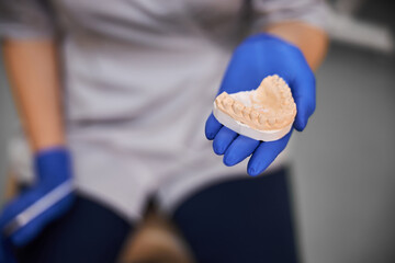 Fototapeta na wymiar Dental technician holding a plaster model of teeth