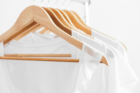 Wooden hangers with white blouses on the counter.