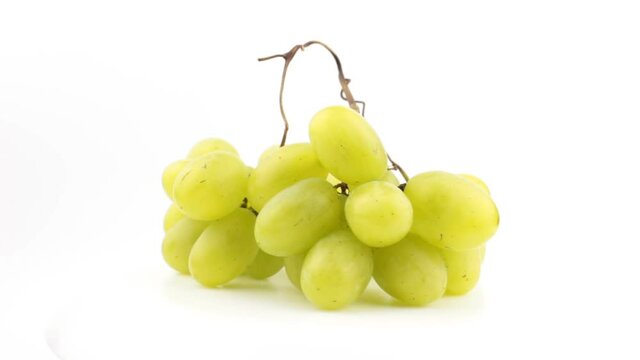 Fresh bunch of juicy grapes rotate on a white background. Ripe juicy grapes rotate on a plate. Close-up of a bunch of white grapes.