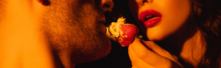 panoramic crop of woman with red lips feeding man with fresh strawberry