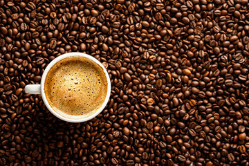 Cup with coffee on the background of coffee beans. View from above