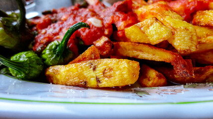 french fries covered with hot organic  tomato sauce closeup in the white plate