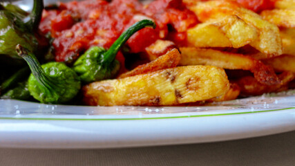 french fries covered with hot organic  tomato sauce closeup in the white plate