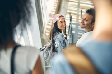 Obraz premium Smiling female and male on an moving staircase in the airport to catch a flight