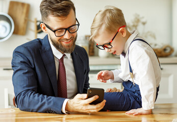businessman father with a young schoolboy son looking at a smartphone.