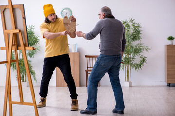 Old man taking lesson from young painter