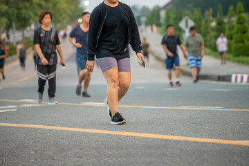 Healthy woman with group of people exercising running , walking on morning park road.