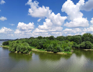 Fototapeta na wymiar White large clouds over the river and trees