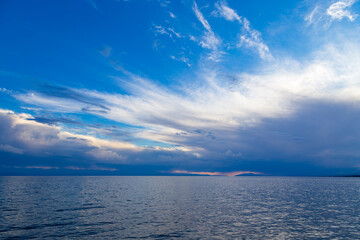 Fototapeta premium Beautiful sunset by the lake. Bright clouds are reflected in the water. Kyrgyzstan.