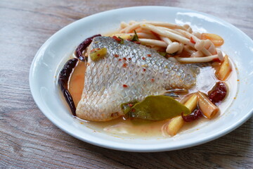 spicy boiled Tilapia or mango fish tail with shimaji mushroon in tom yum soup on plate