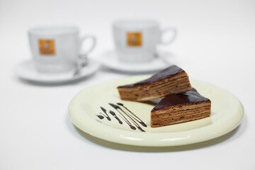 tasty chocolate cake on plate and cup of coffee on white background