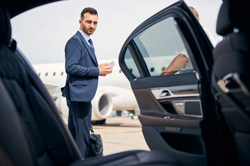Successful businessman standing by the car looking determined