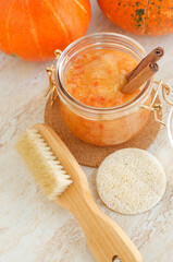 Pumpkin spice scrub with sugar and cinnamon in a glass jar and wooden body brush. Homemade beauty treatment and spa recipe.