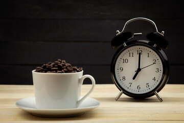 Fototapeta na wymiar White cup with coffee grains on the background of the clock