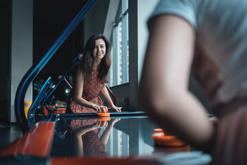 beautiful brunette female playing air hockey with friend
