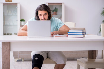 Young leg injured student studying at home