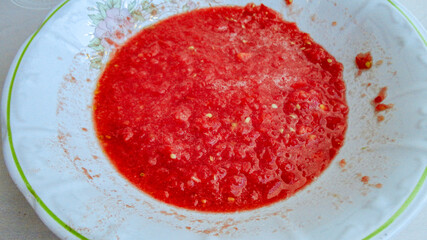 Red liquid organic tomato sauce in a white pot 