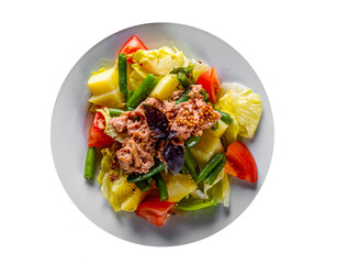Salad nicoise. Tuna, with green beans, tomatoes, potatoes and a vinaigrette mustard dressing in white plate isolated on white background