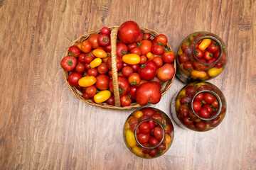 In the photo there is a basket with tomatoes. Fresh organic food from the garden. In the background are jars of canning for the winter.
