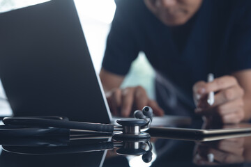 Doctor working on laptop computer and digital tablet in medical office