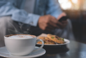 Man sitting at table in coffee shop and using mobile phone in the morning