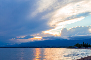 Beautiful sunset by the lake. Bright clouds are reflected in the water. Kyrgyzstan.