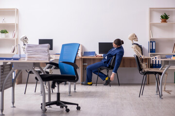 Young male employee with skeletons in the office