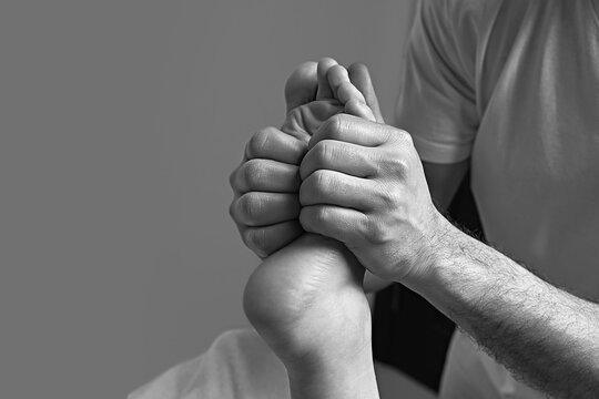 Male masseur doing massage on female foot reflex zone in the spa salon.