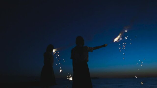 夕暮れに花火をする女子高生