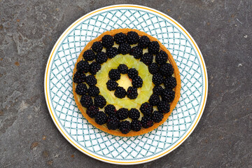 A key lime pie topped with fresh blackberries and lime slices